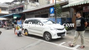 Petugas Dishubkominfo sedang menggembok mobil Avanza yang parkir di lokasi untuk motor.
