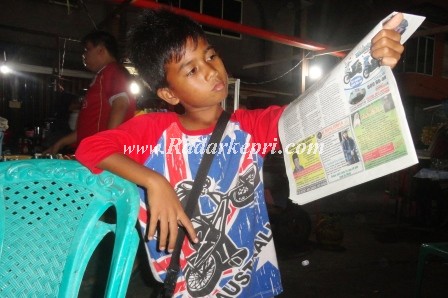 Reki, seorang anak penjual koran di kota Tanjungpinang sedang menawarkan koranya di Akau Potong Lembu.