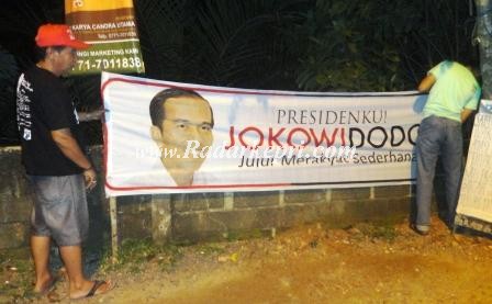 Dua orang relawan Jokowido untuk Presiden sedang memasang spanduk sosialisasi.
